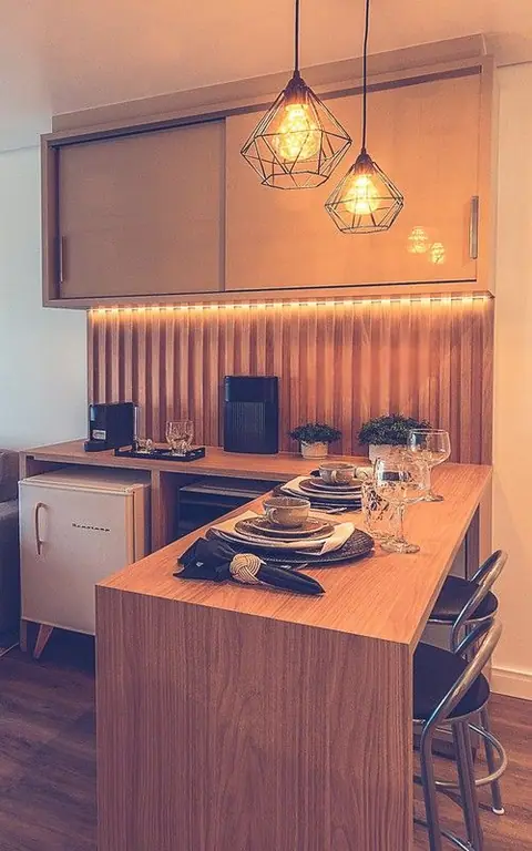 Cozinha compacta com fita de LED sob os armários, pendentes aramados e bancada de madeira